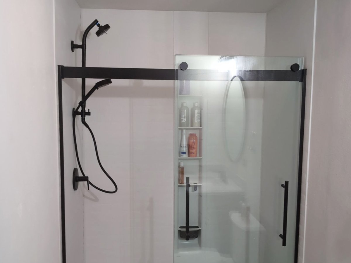 Modern guest bathroom with a walk-in shower, black fixtures, and sliding glass door after a bathroom remodel in Steamboat Springs, Colorado.