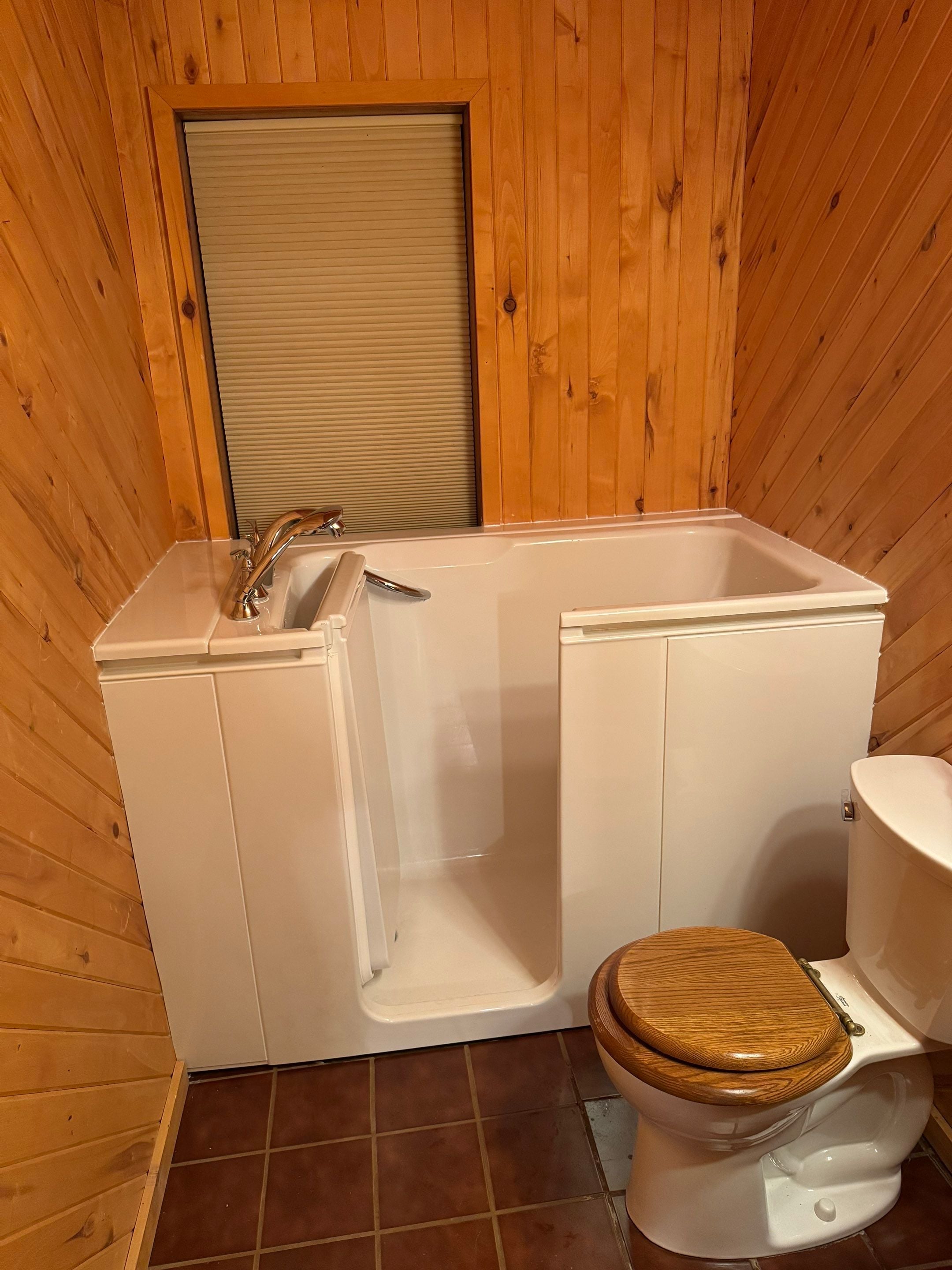 Walk-in tub installed in rustic-style Alamosa, CO bathroom with wood-paneled walls and safe-entry design.