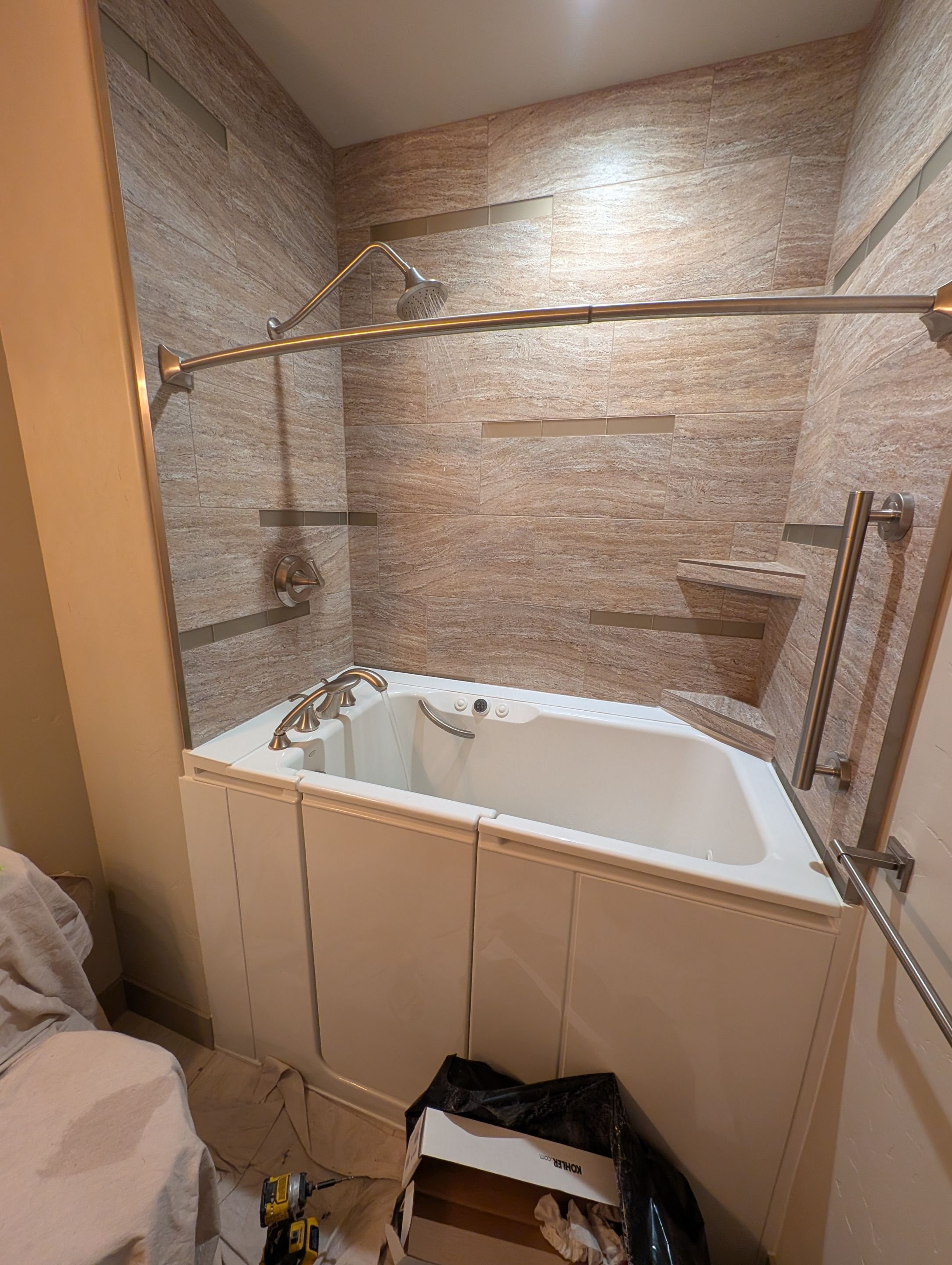 Bathroom remodel on Amber Spring Court in Grand Junction featuring a walk-in tub with stone-look wall panels, built-in shelving, and upgraded fixtures for safety and comfort.