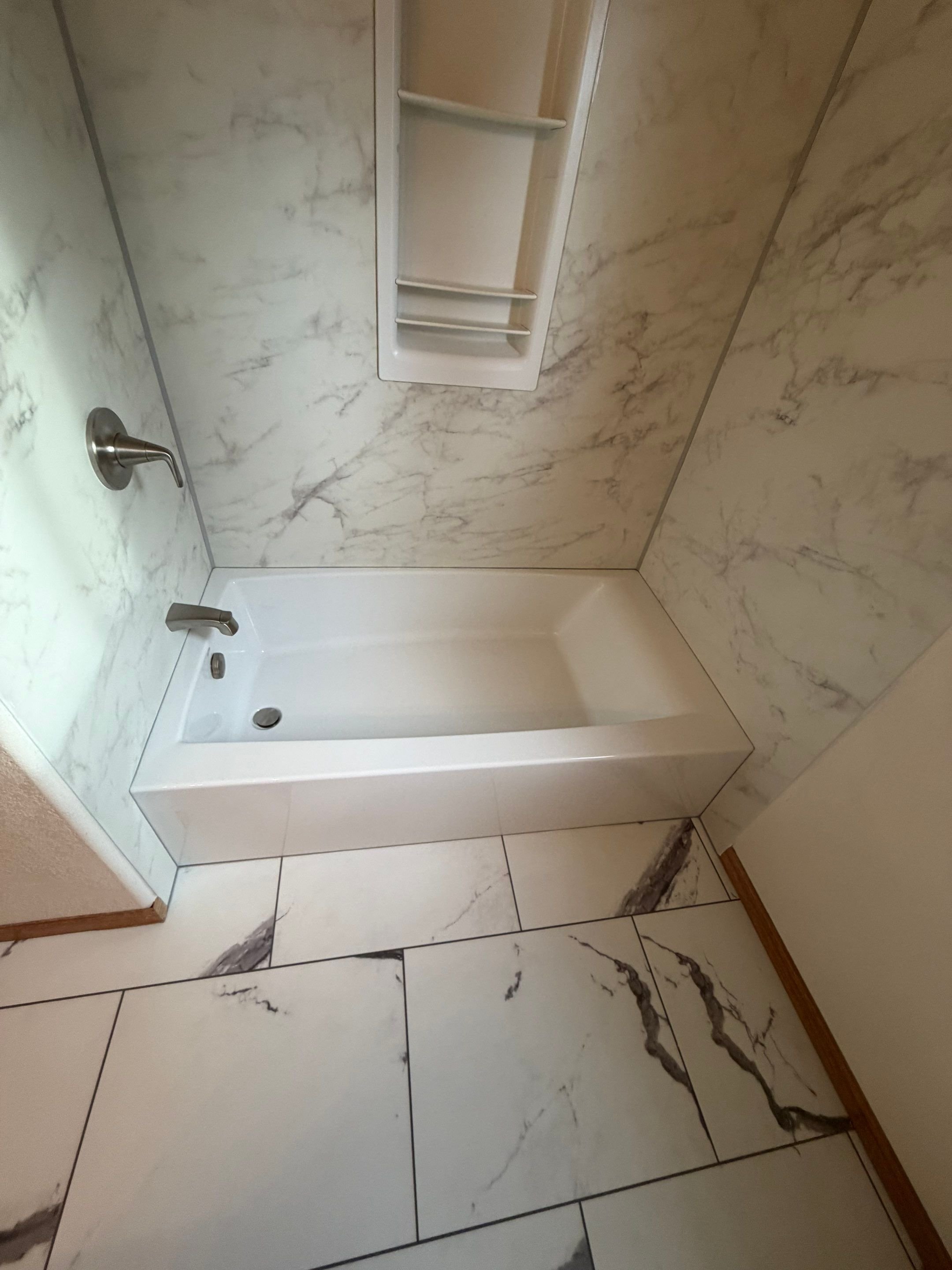 Bathroom remodel on Ashmount Drive in Fort Collins featuring a modern tub and shower with marble-look wall panels and upgraded fixtures