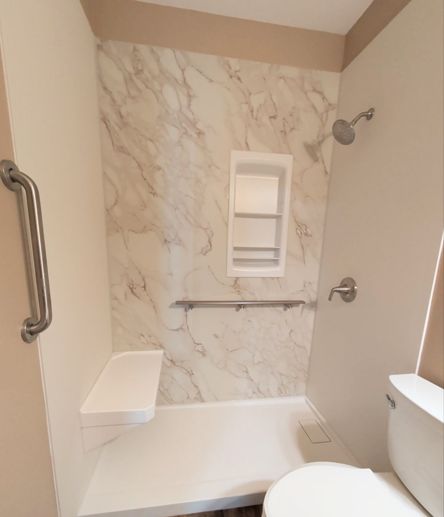 Accessible walk-in shower in Evergreen, CO, with built-in seating, grab bars, shelving, and a low-threshold entry.
