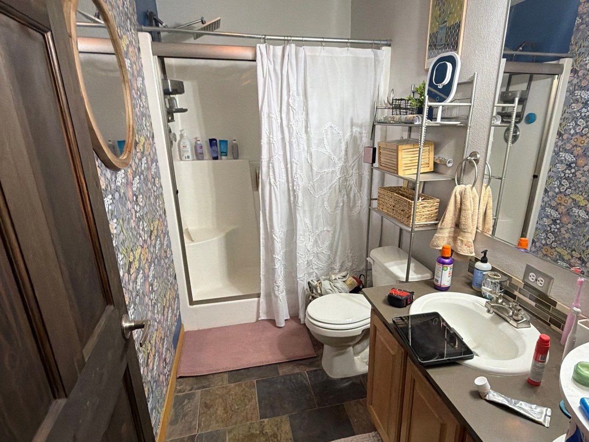 Before photo of the guest bathroom with an older shower, vanity, and flooring before a bathroom remodel in Steamboat Springs, Colorado.