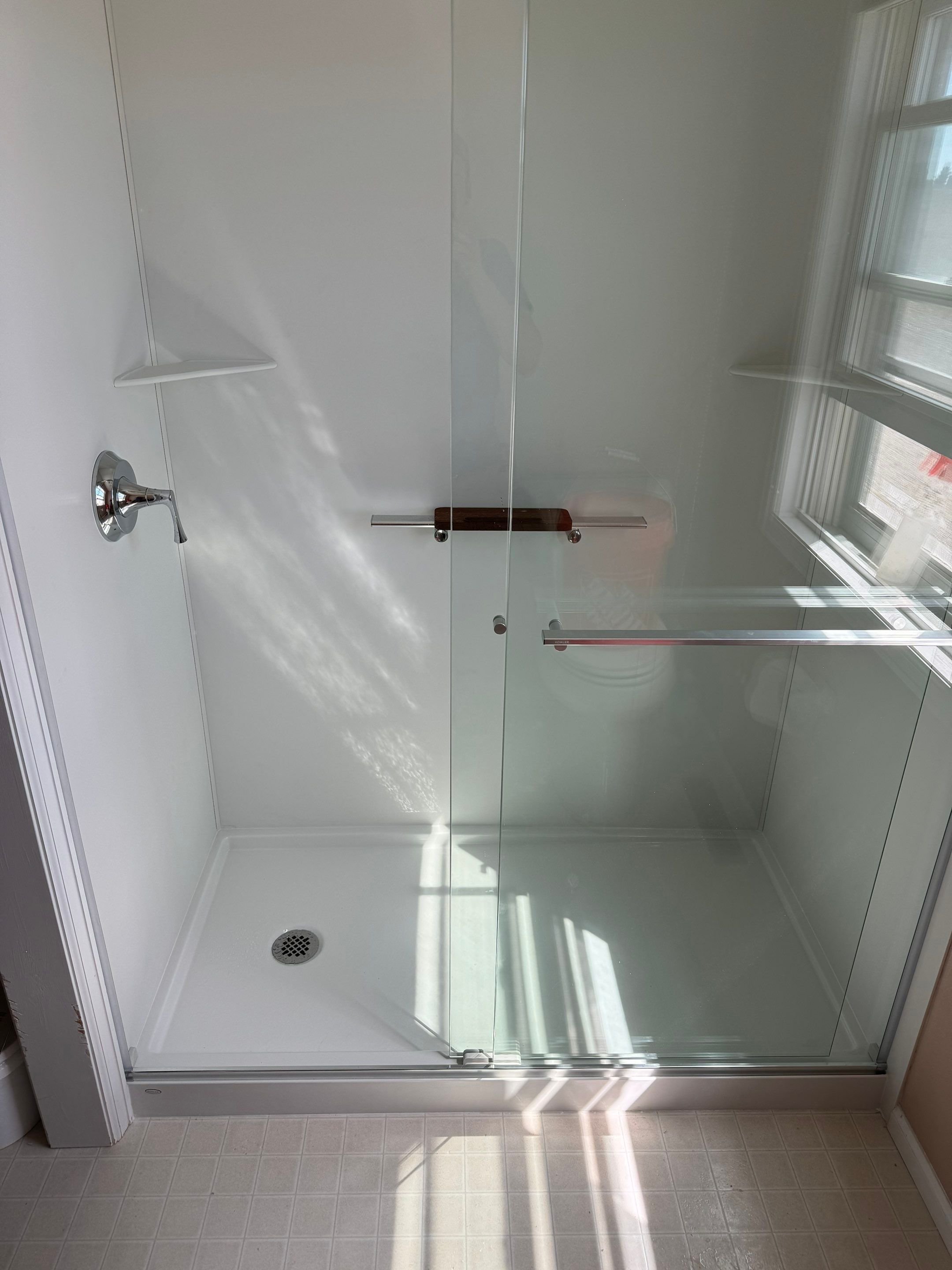 Walk-in shower remodel on Blazer Road in Cheyenne, WY featuring low-threshold base, sliding glass doors, and moisture-resistant wall panels
