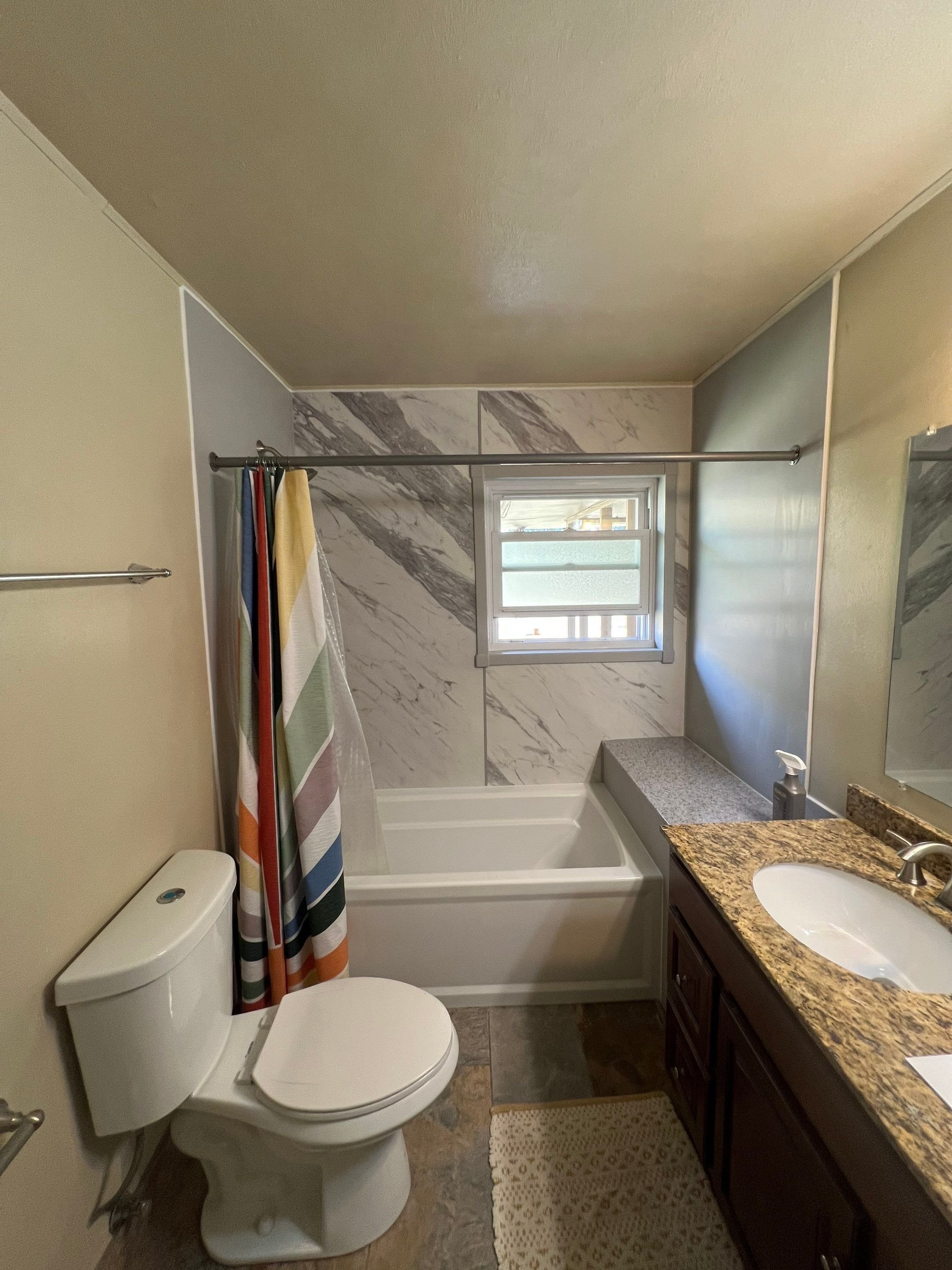 Bathroom remodel in Littleton, CO on Broadmoor Drive featuring a tub-to-shower upgrade with marble-look wall panels, updated vanity, and improved ventilation.