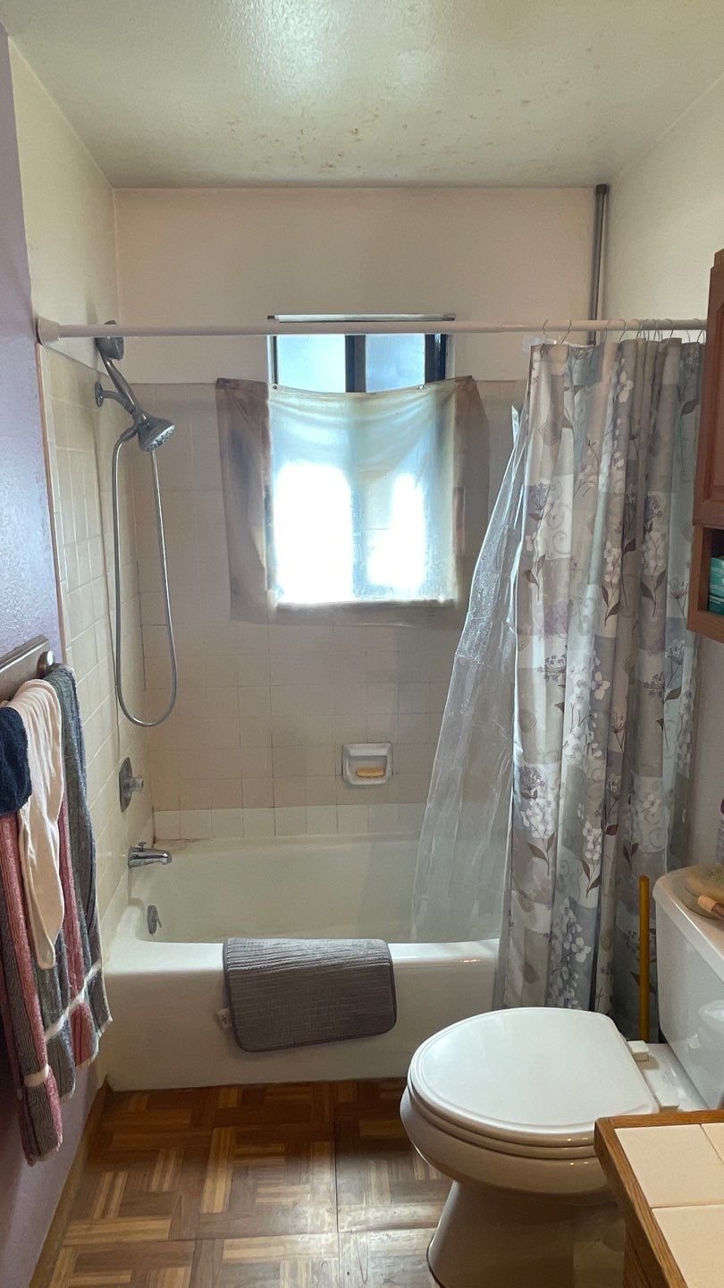 Before photo of an older bathroom on Broken Spoke Road in Grand Junction showing a builder-grade tub, limited ventilation, and aging tile common in older homes.