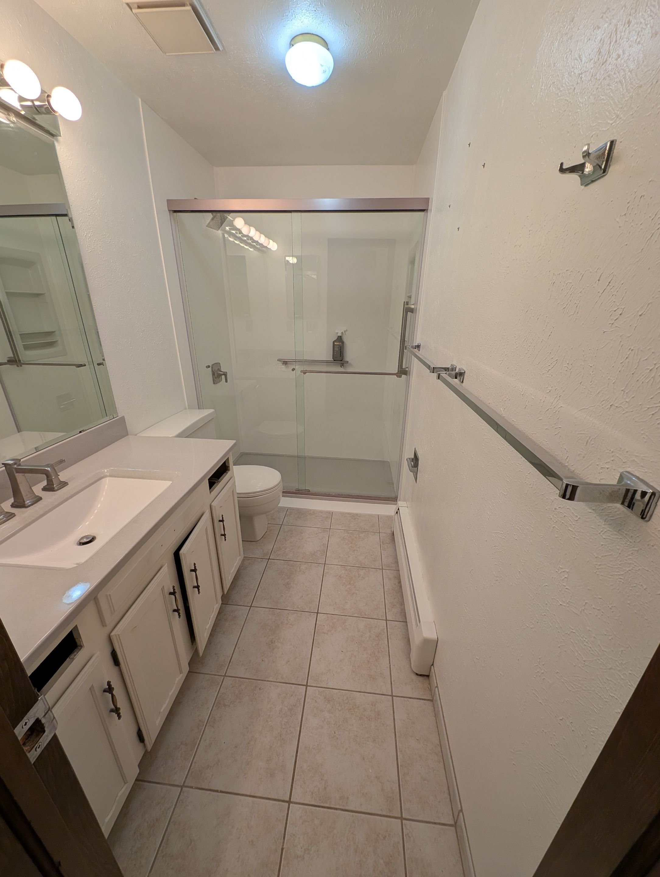 Bathroom remodel in Lakewood on Chase Lane featuring a tub-to-shower conversion with sliding glass doors, updated vanity, improved lighting, and durable finishes designed for Front Range homes.