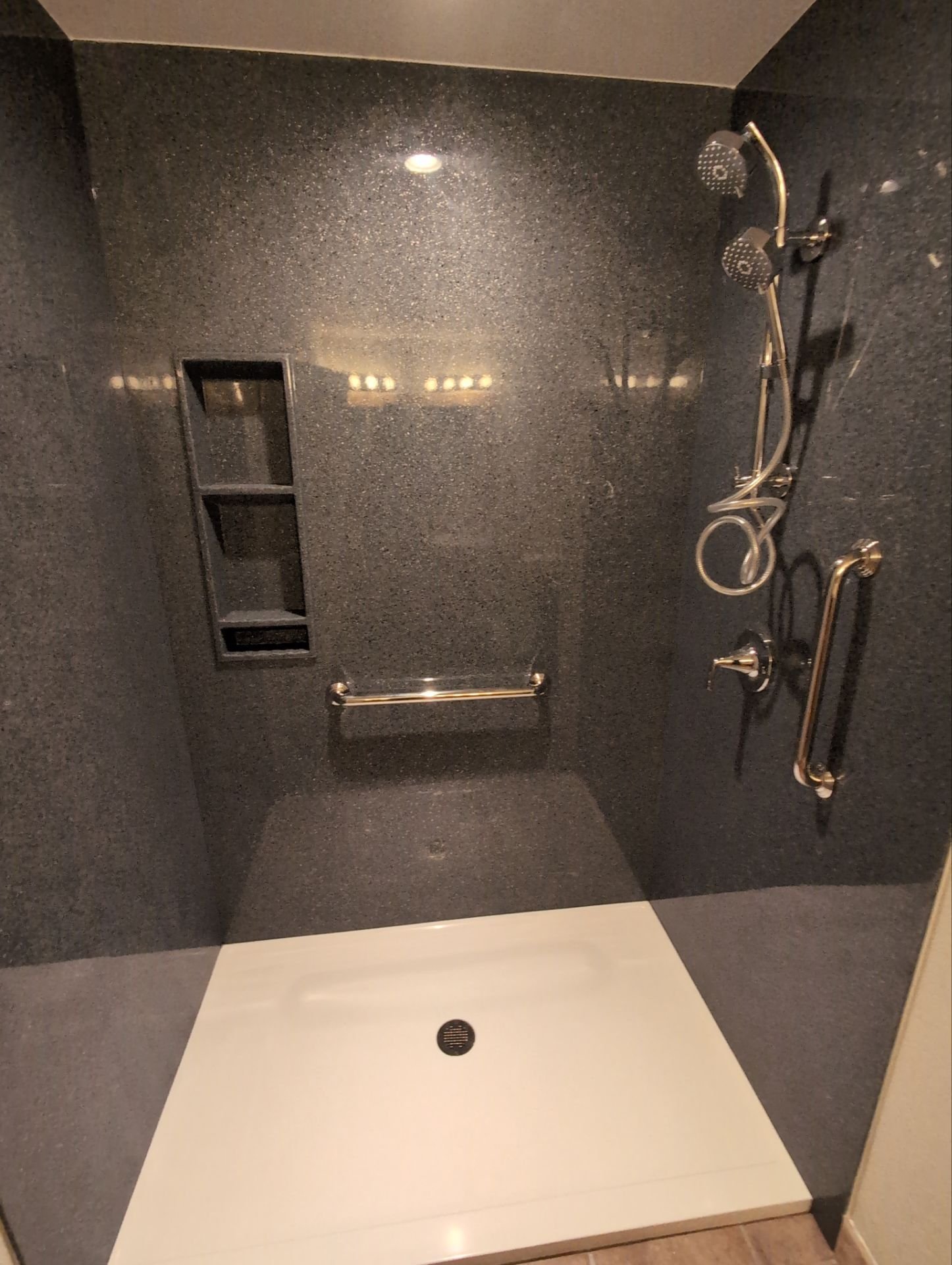 Tub-to-shower conversion on E 11th Street in Loveland showcasing a spacious walk-in shower with solid-surface walls, built-in grab bars, and accessibility-focused design.