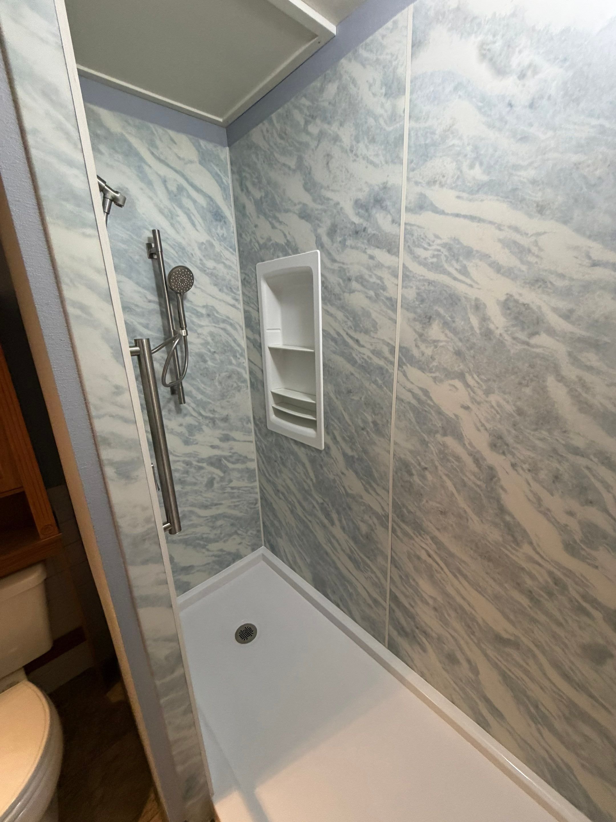 Bathroom remodel on E 42nd Street in Loveland with marble-look wall panels, a low-threshold shower base, and modern fixtures designed for hard-water conditions.