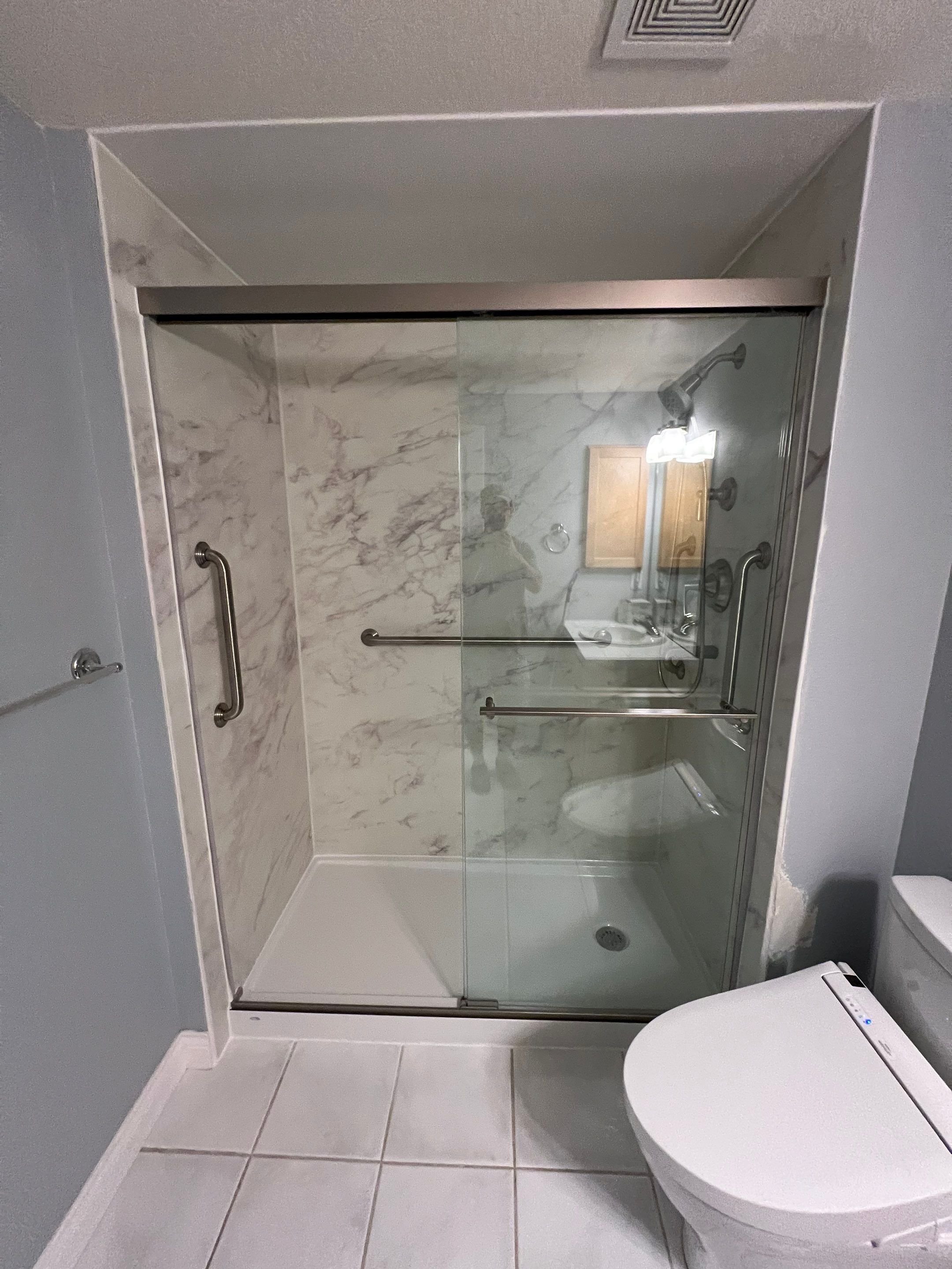 Denver bathroom remodel on E Cedar Avenue with walk-in shower, frosted glass panel, built-in shelving, and improved accessibility for everyday use