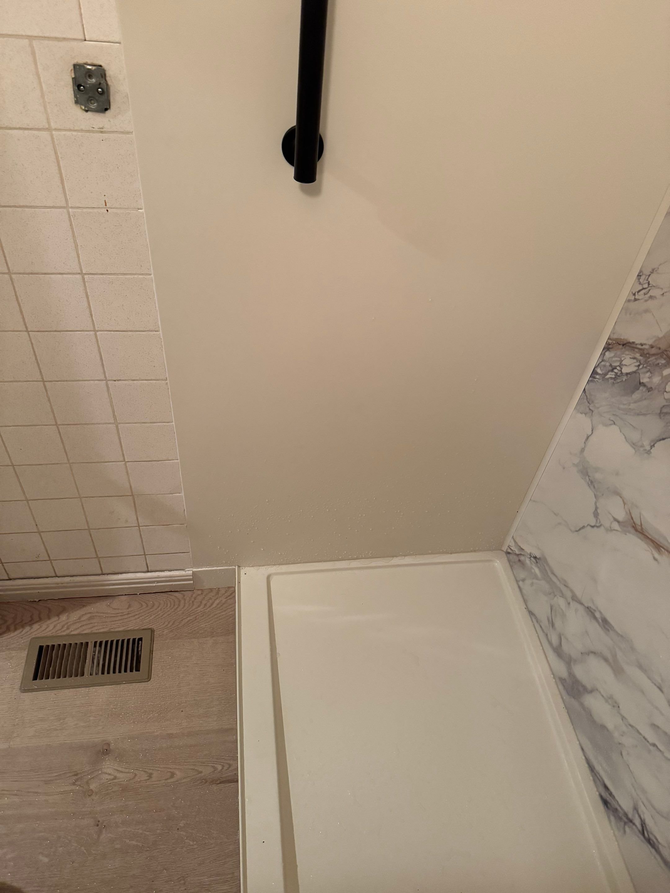 Bathroom remodel flooring transition next to new walk-in shower base in Aurora, CO – updated vinyl plank and wall panel installation.
