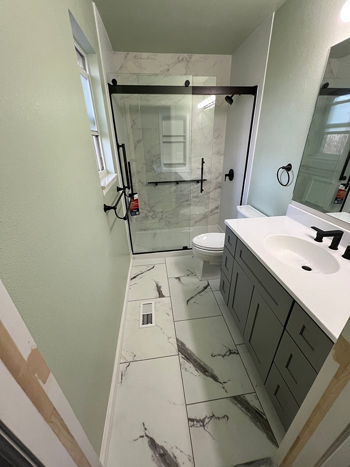 Modern KOHLER bathroom remodel in Florence with glass shower doors and green walls