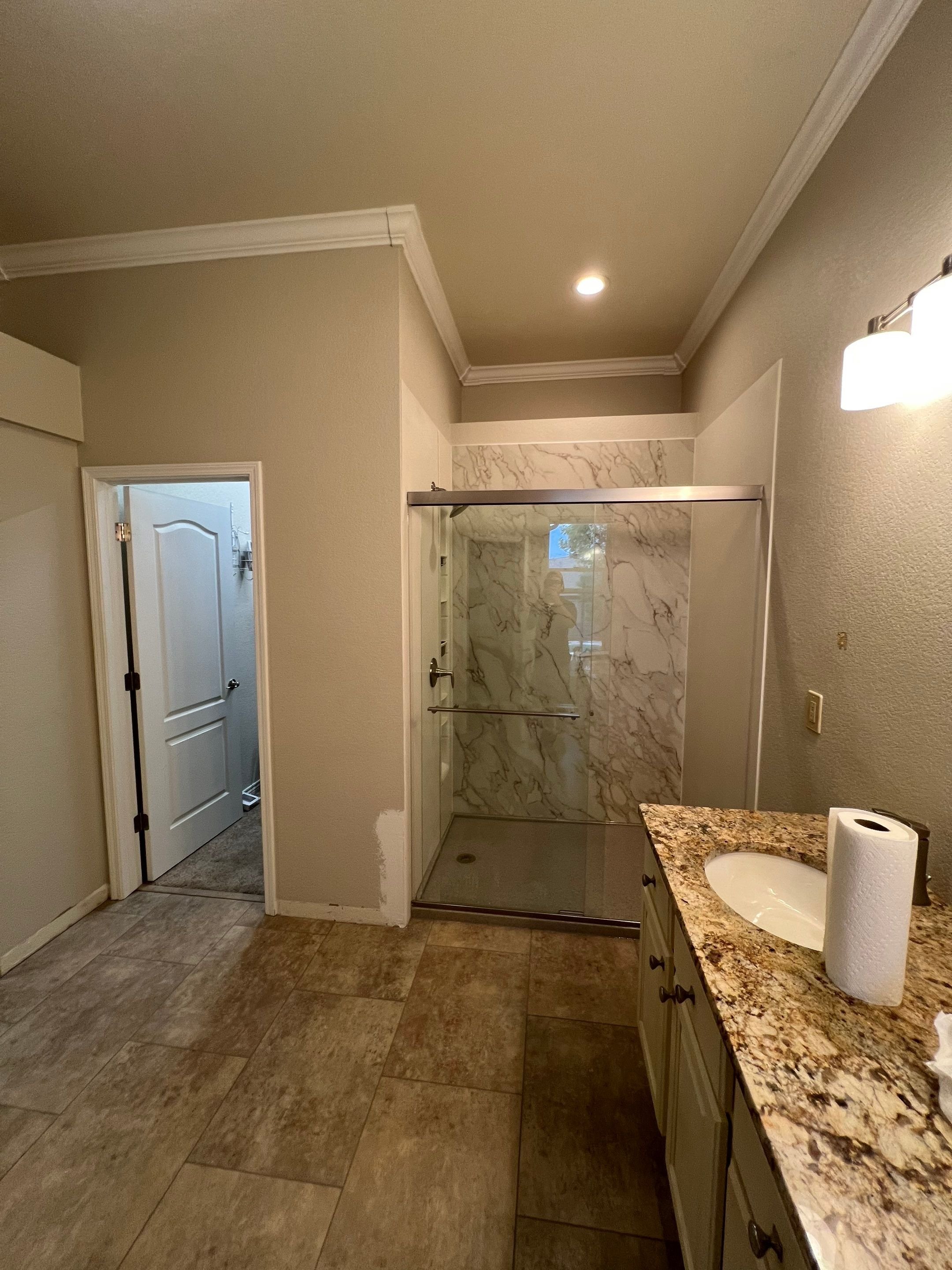 Full bathroom shower remodel in a Colorado Springs home on Grand Carriage Grove with framed glass doors, upgraded lighting, and modern wall panels