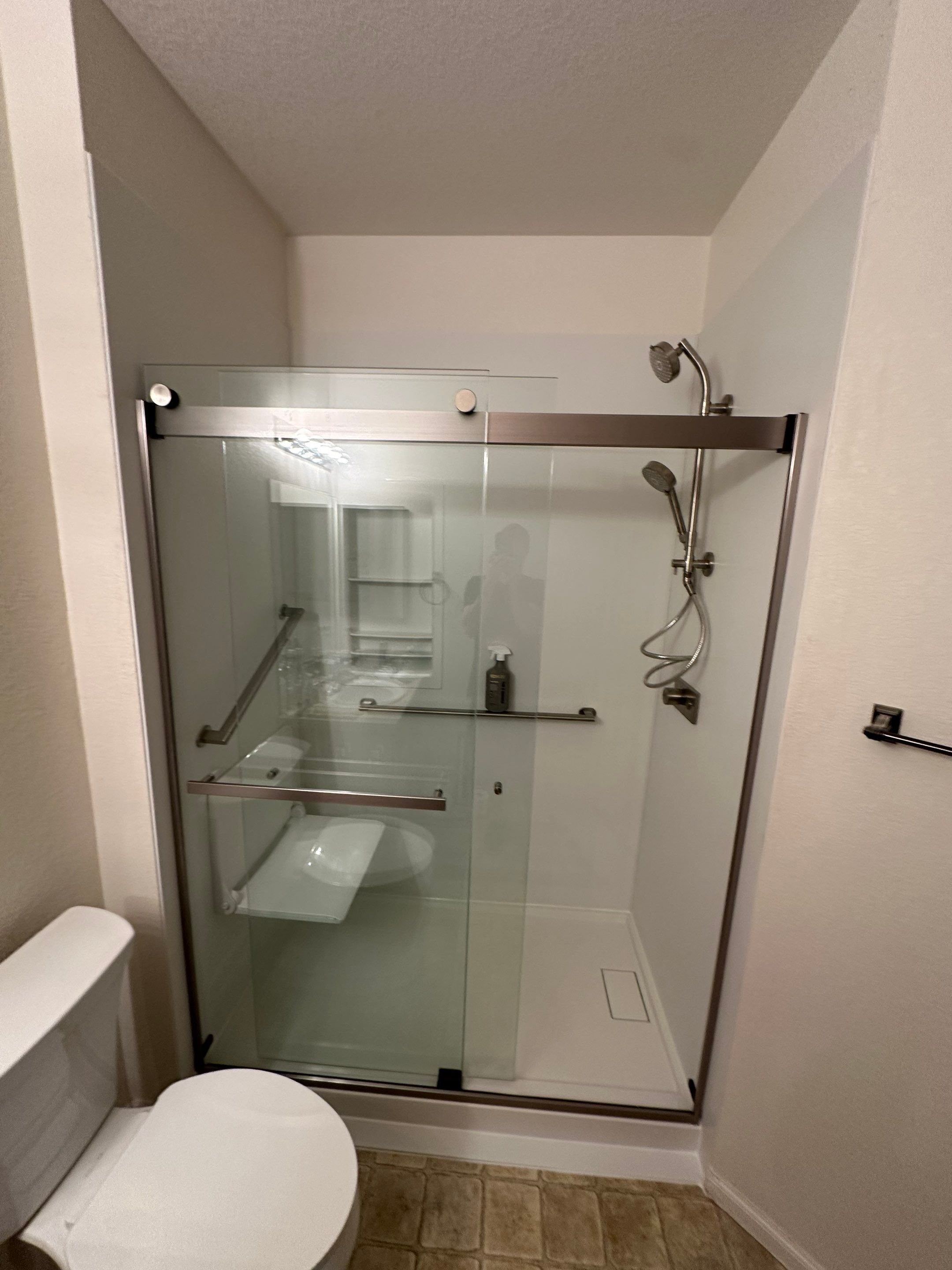 Walk-in shower installation on Grays Peak Drive in Loveland featuring a dark solid-surface shower pan, recessed shelving, and slip-resistant flooring for long-term safety.