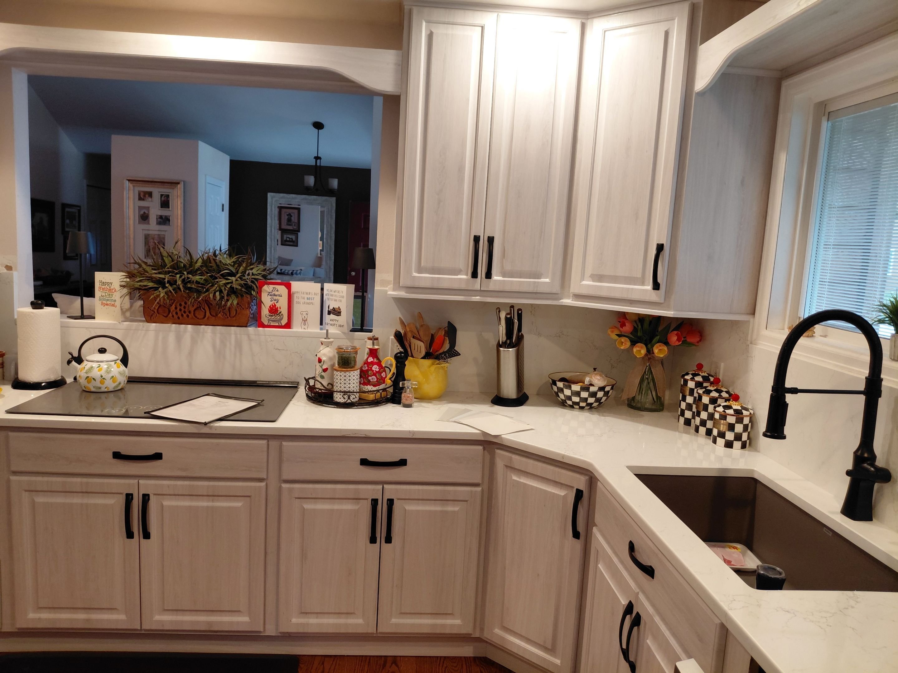 Whitewashed wood kitchen cabinet restyling in Arvada, CO with black hardware and marble-look countertops
