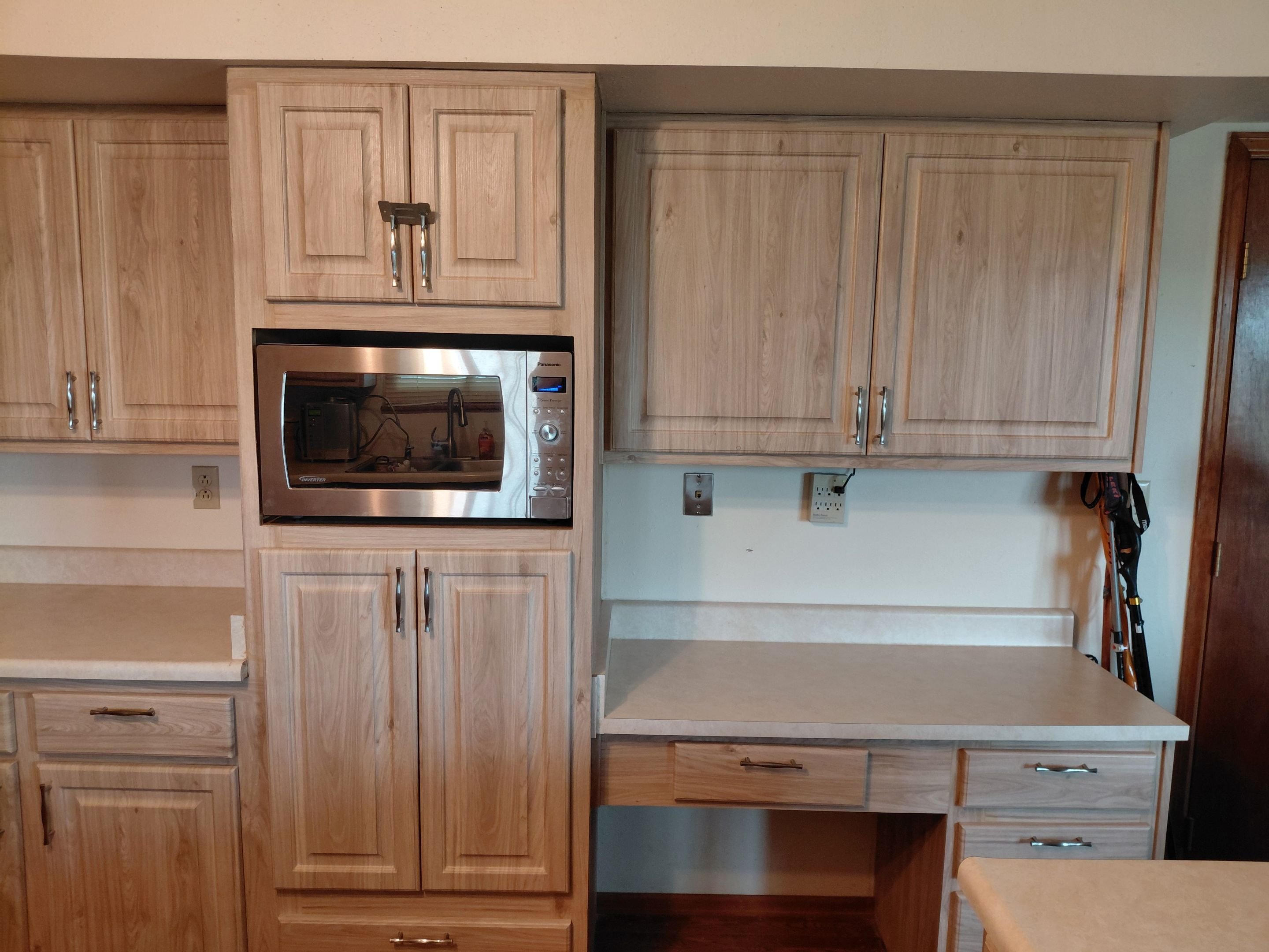 Light oak kitchen cabinet restyling in Colorado Springs, CO with built-in microwave and desk area