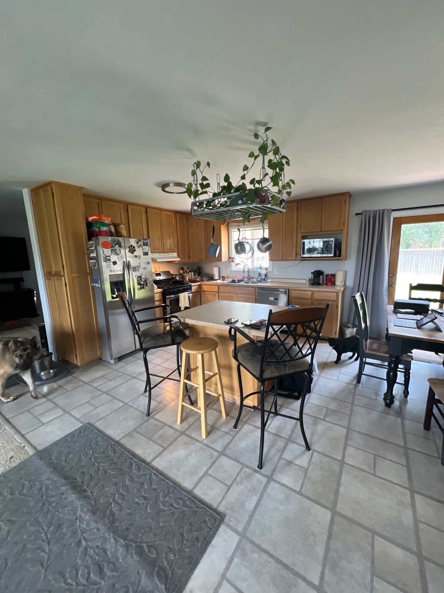 Natural wood kitchen cabinet restyling in Greeley, CO with center island, stainless steel appliances, and tile flooring