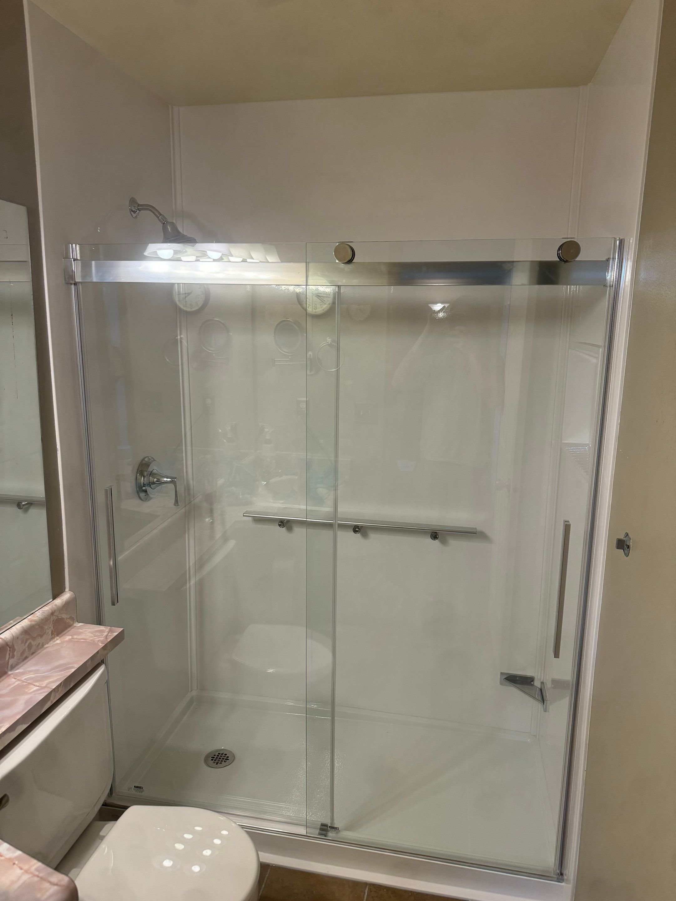 Tub-to-shower conversion in a Colorado Springs bathroom on Little Pine Circle featuring low-threshold entry, marble-style walls, and safety grab bars
