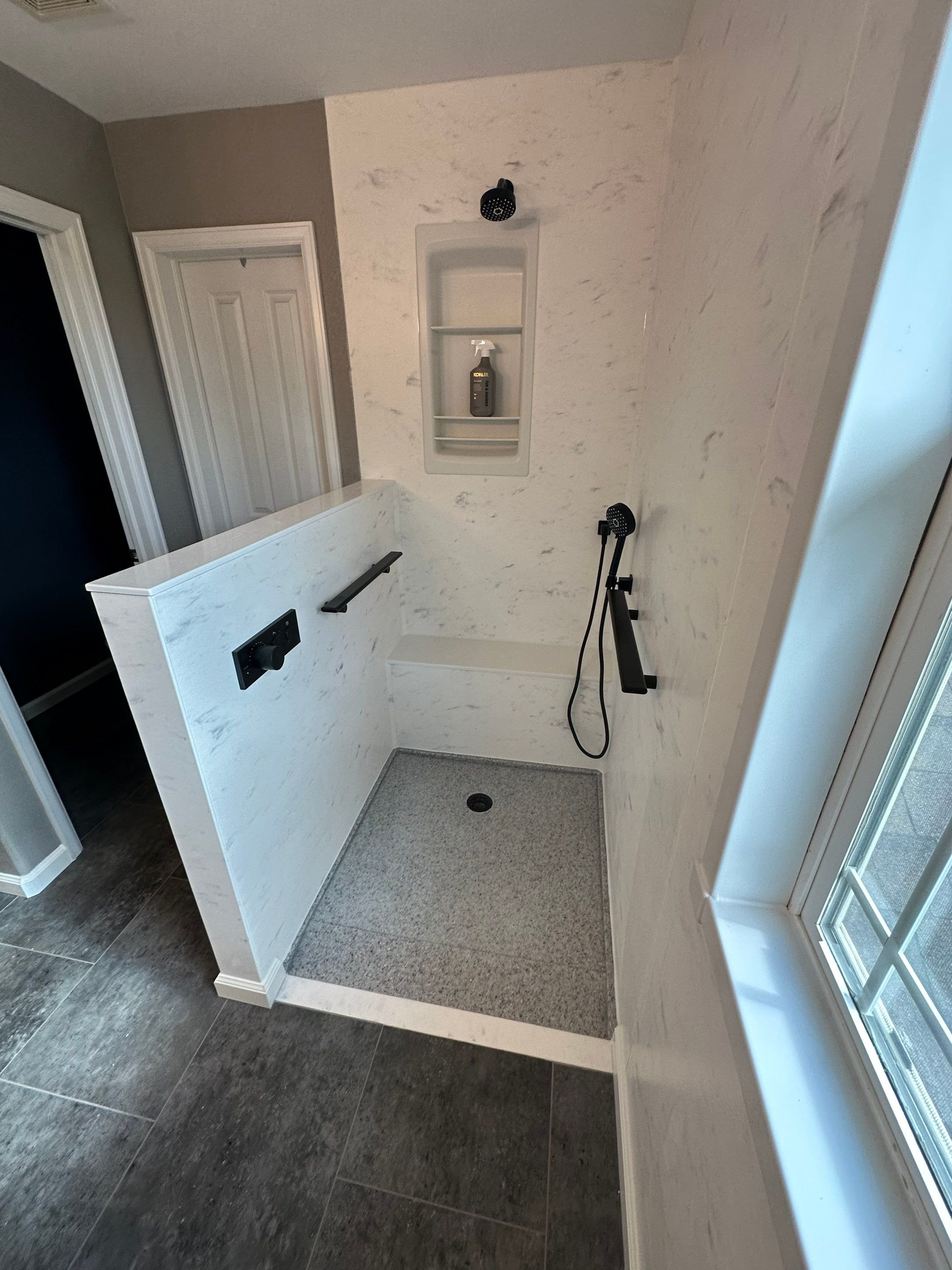 Barrier-free shower with matte black fixtures and granite base
