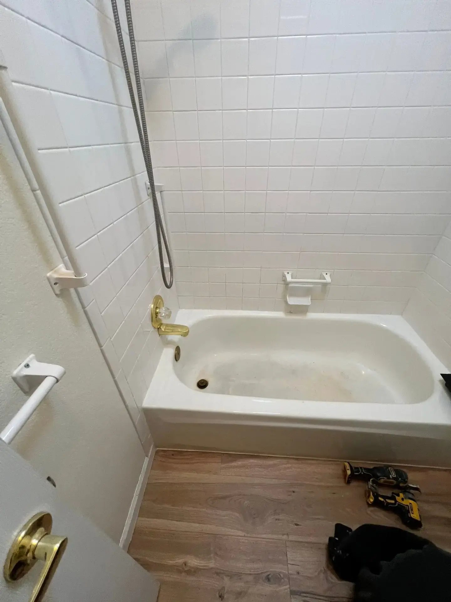 Outdated bathtub with tile surround and brass fixtures prepared for a tub-to-shower conversion remodel.