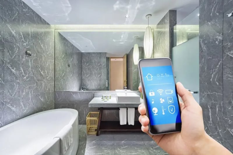 Modern smart bathroom with marble finishes, freestanding tub, vessel sink, and smartphone controlling smart home features like lighting, temperature, and music.