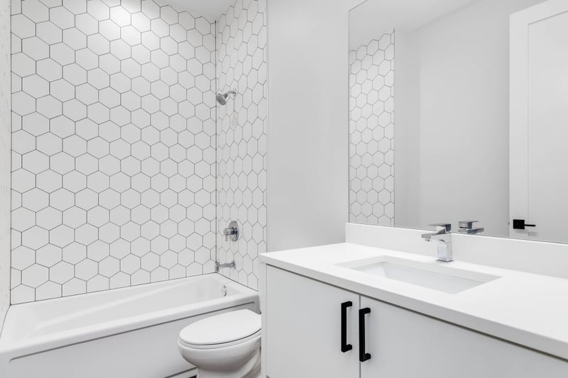 Modern white bathroom with hexagon tile shower, standard tub, single-sink vanity, and chrome fixtures