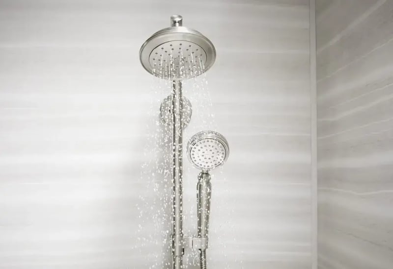 Kohler WaterSense showerhead with handheld sprayer running in a modern Colorado bathroom with solid-surface shower walls