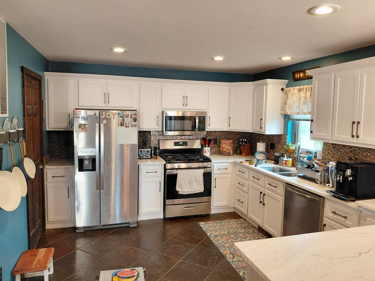 Updated kitchen with professionally refinished white cabinets and new hardware after a kitchen cabinet remodel in Steamboat Springs, Colorado.
