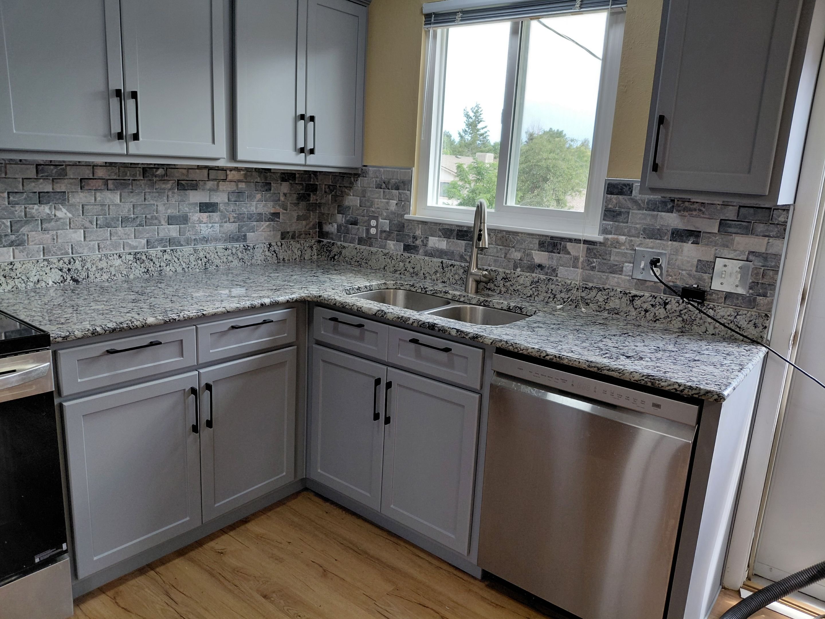 Modern kitchen remodel in Aurora, CO with gray shaker cabinets, granite countertops, subway tile backsplash, and stainless-steel appliances