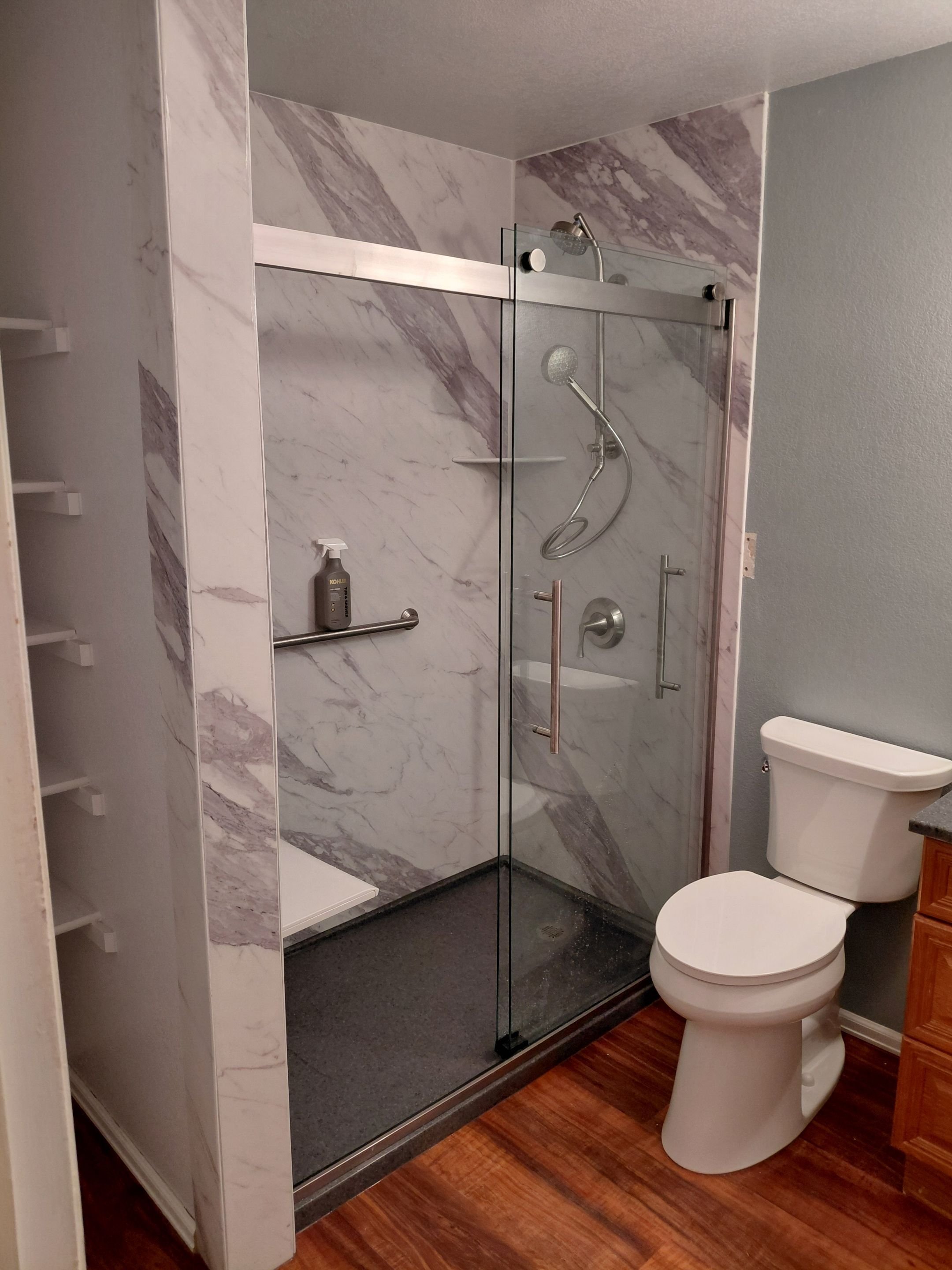 Bathroom remodel on Northridge Drive in Grand Junction with a glass-enclosed shower, stone-look wall panels, upgraded fixtures, and improved accessibility.