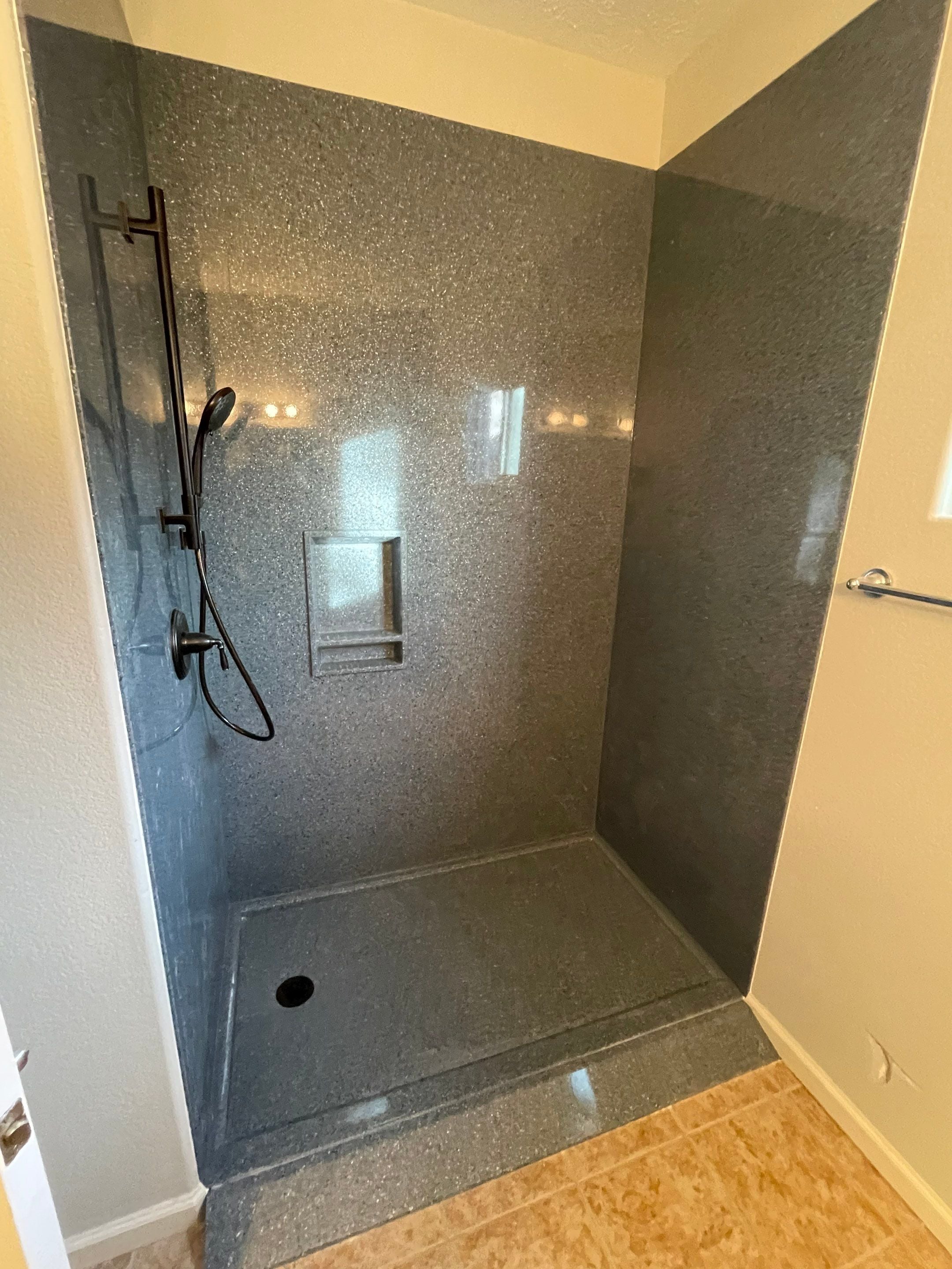 Onyx shower system with accessibility ramp, matte black handheld showerhead, and recessed shelf in Grand Junction bathroom remodel by HomePride Bath