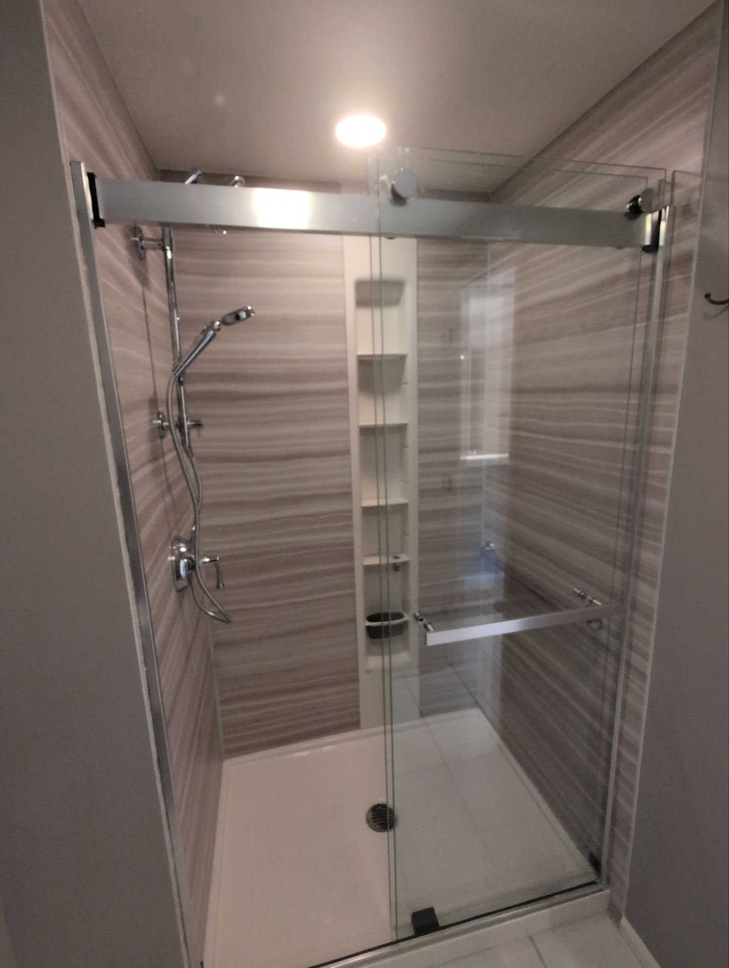 A modern new walk-in shower with sliding glass door installed on S Jersey Way in Centennial, Colorado