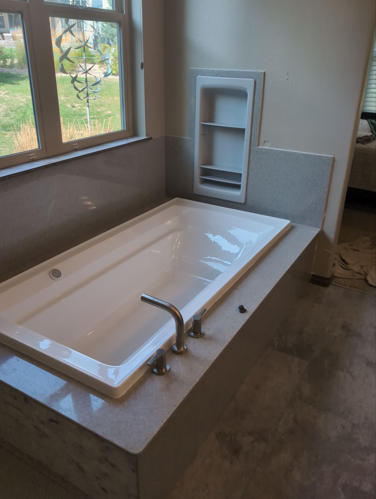 Modern bathtub remodel completed on S Joyce Street in Lakewood with solid-surface wall panels, built-in shelving, and low-maintenance materials suited for Colorado hard water.