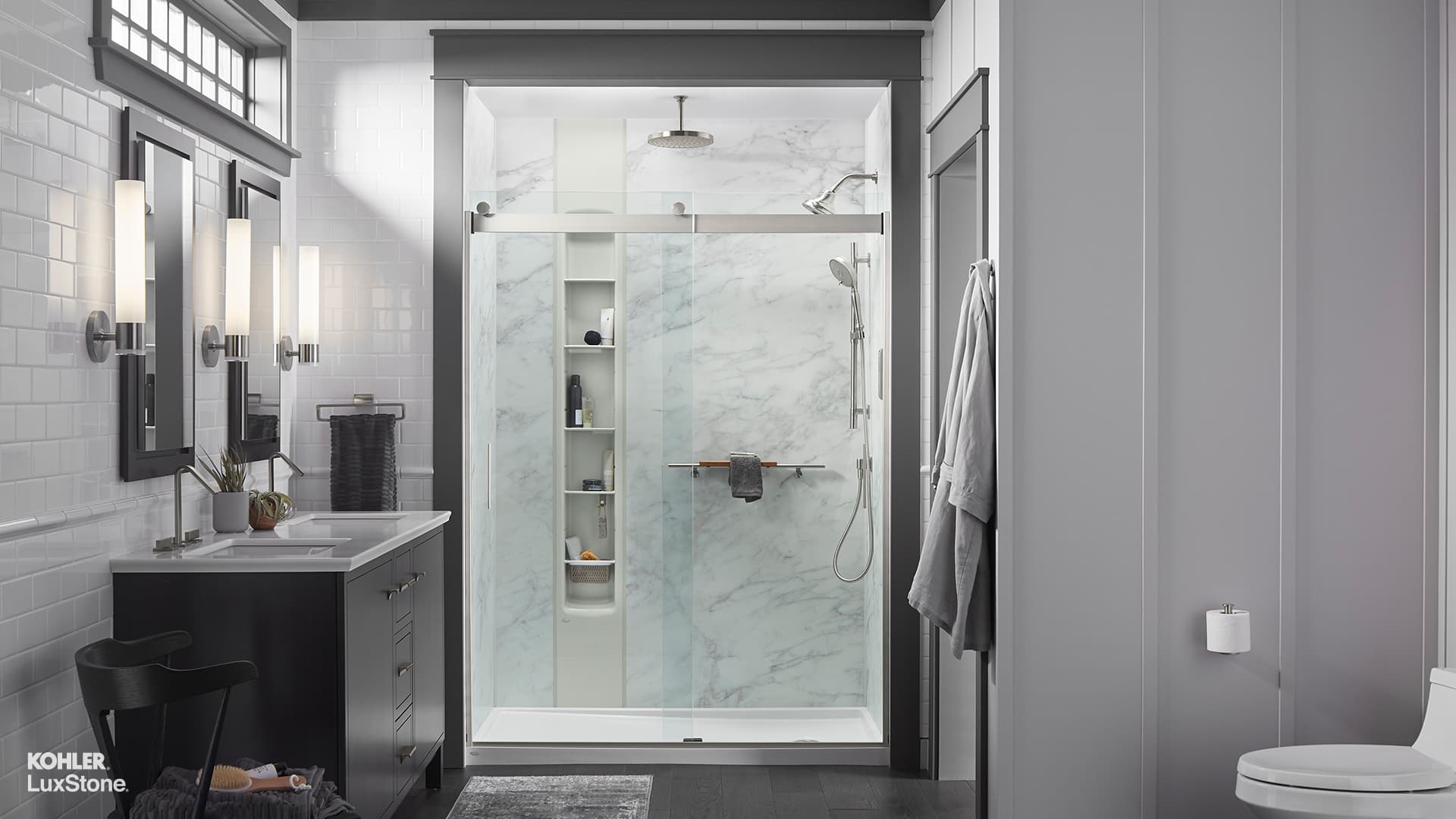Modern KOHLER LuxStone walk-in shower with stone-look panels, frameless glass door, and built-in bench in a contemporary Colorado bathroom remodel.