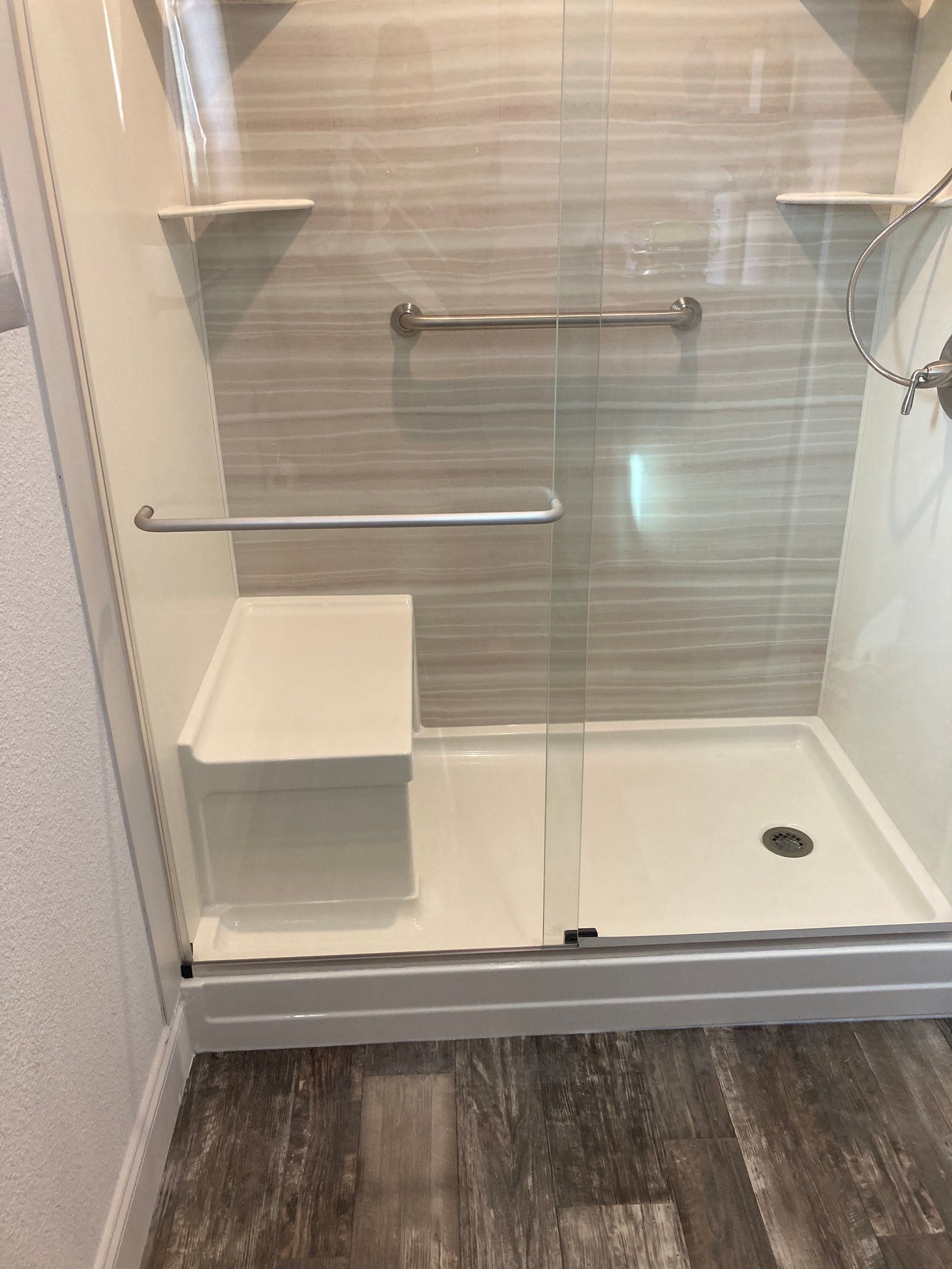 Built-in shower seat with grab bars and glass doors