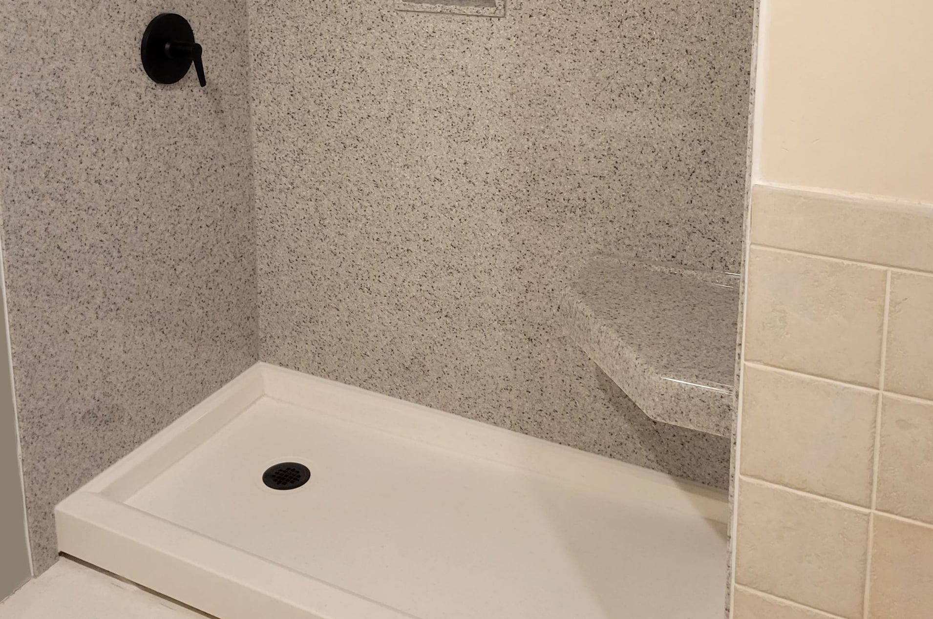Stone-look shower with granite walls and corner seat