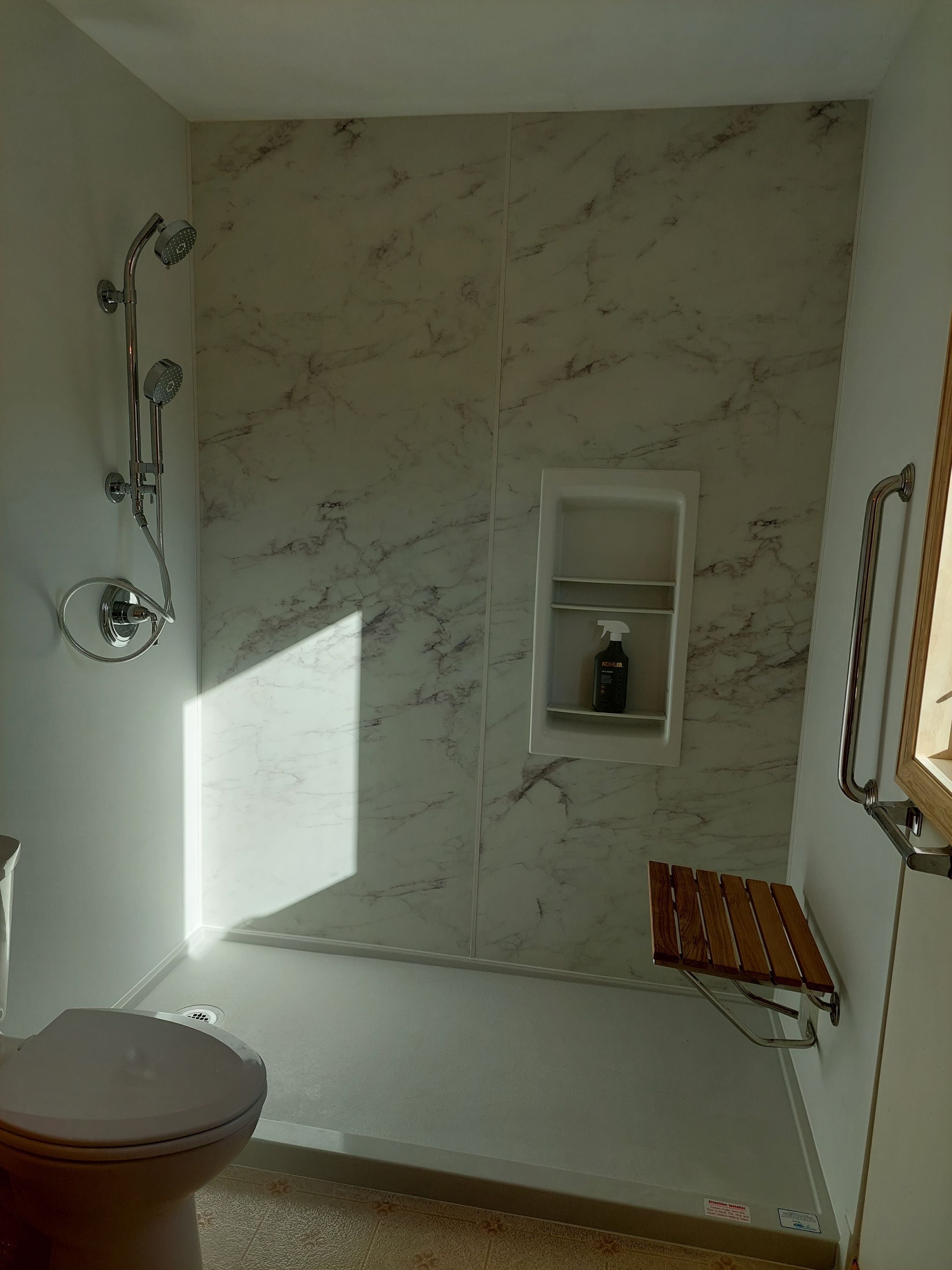Marble-look shower with dual shower heads and built-in shelving