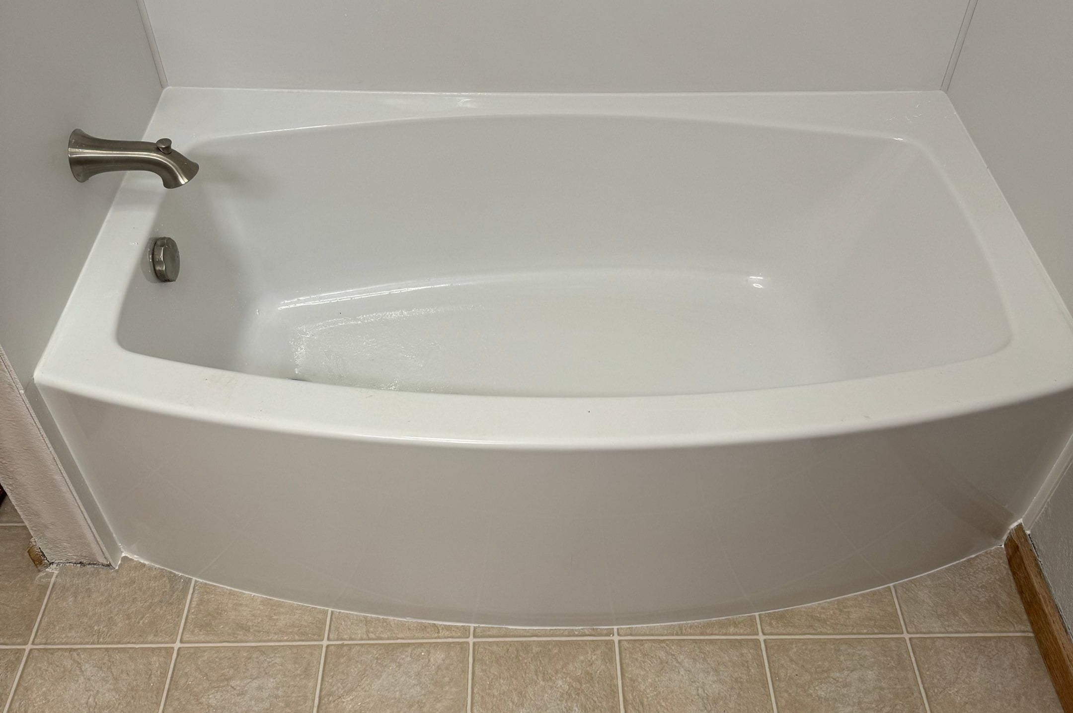 Tub-to-tub remodel in Holyoke, Colorado with a sleek white curved bathtub, brushed nickel faucet, and light tile flooring.