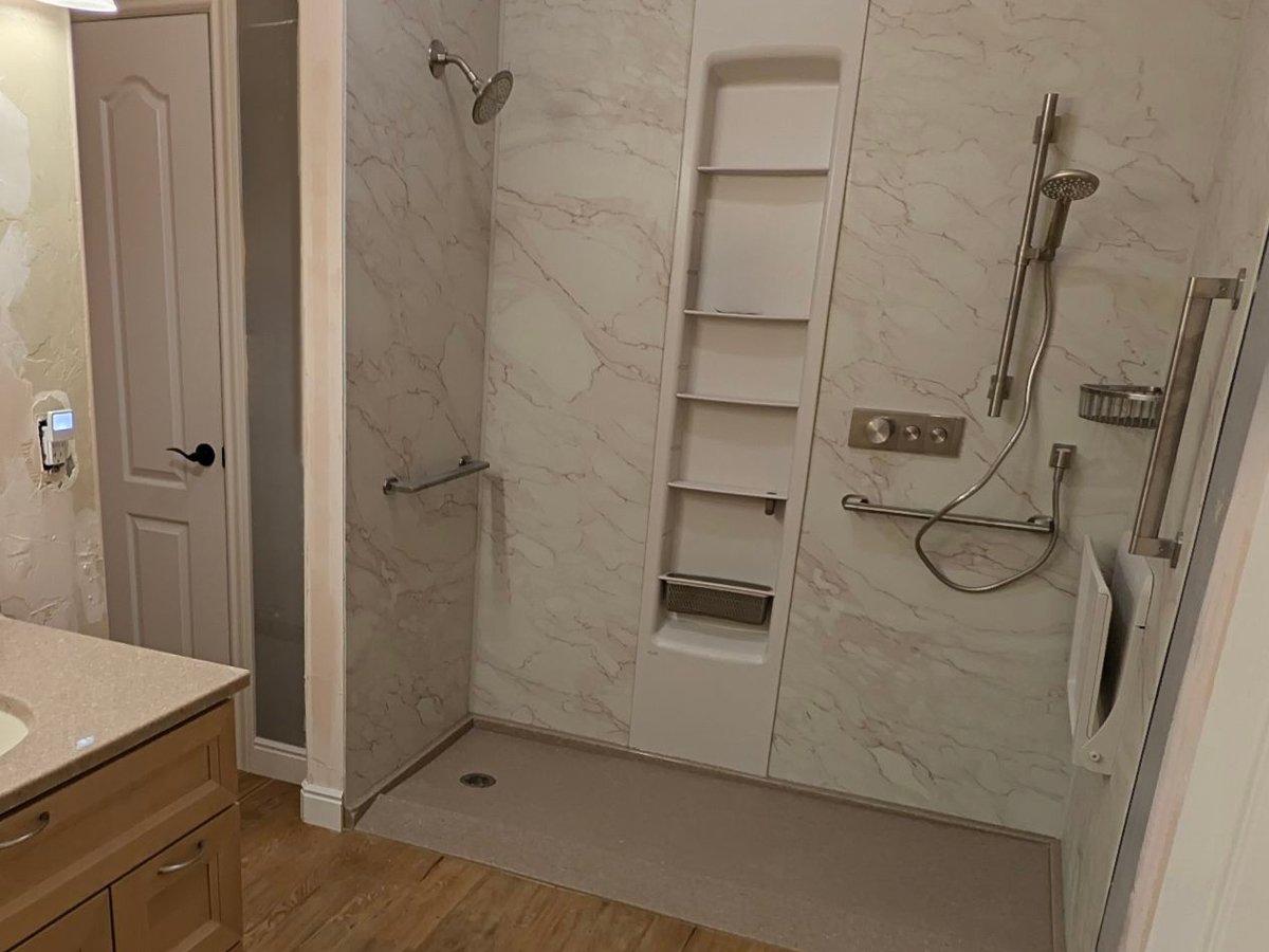 Low-threshold walk-in shower with grab bars, a fold-down seat, handheld shower on a slide bar and built-in shelving in a Colorado home