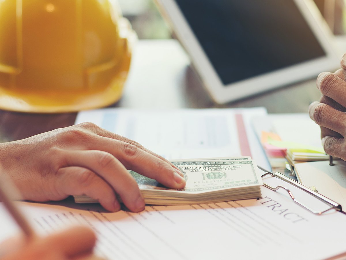 Homeowner reviewing bathroom remodel change order costs with contractor during construction planning meeting, showing budget adjustments and renovation paperwork.