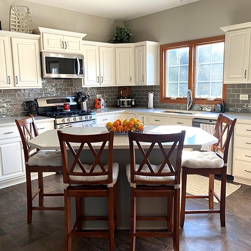 Remodeled kitchen with white satin cabinets, gray subway tile backsplash, and stainless steel appliances.
